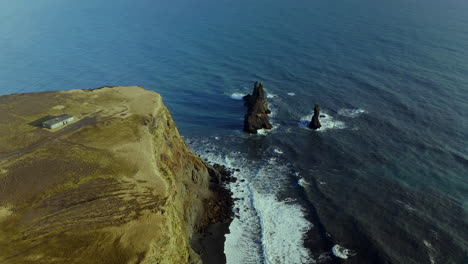 famosas pilas marinas de basalto de reynisdrangar con olas salpicadas en los acantilados costeros en la playa de reynisfjara en el sur de islandia