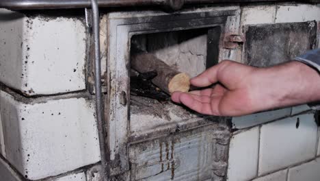 el hombre abre la puerta y pone madera en una cocina rústica antigua