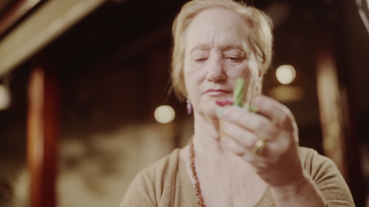 An older woman meticulously crafting or examining a small decorative item