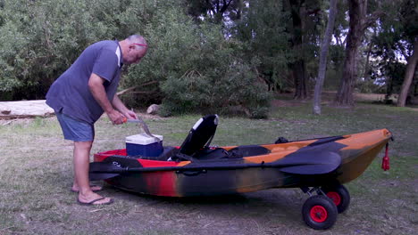 un pescador sacando su captura de una caja de hielo en el kayak y procede a limpiar el pescado