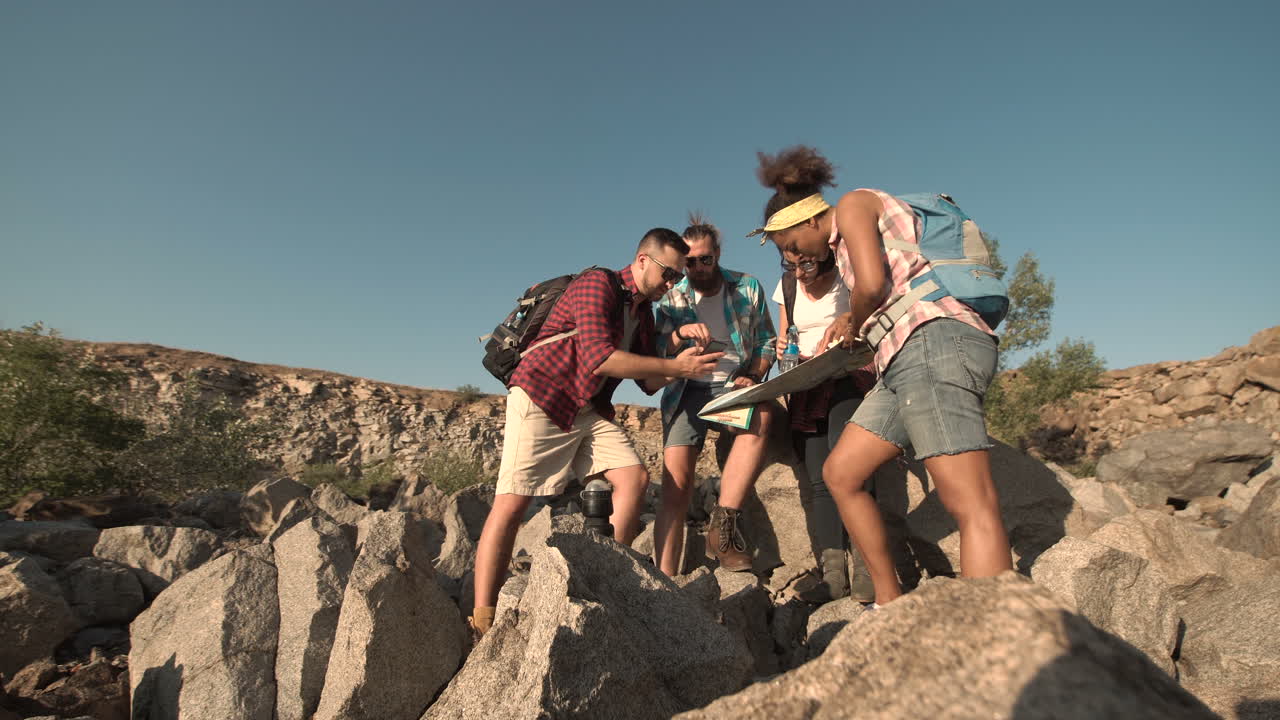 Group of hikers navigating with a map and smartphone in a rocky landscape