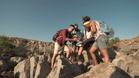 group of hikers navigating with a map and smartphone in a rocky landscape