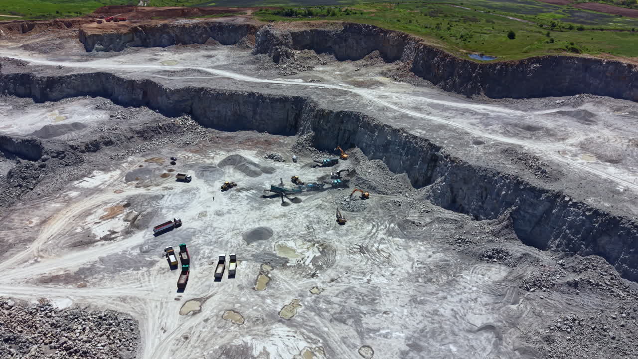 Mining operation in a quarry with heavy machinery working on stone extraction in a rural area during daylight