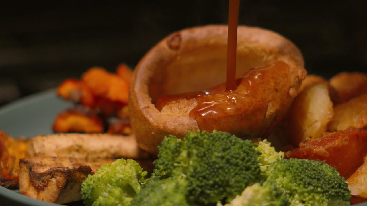 British Roast Dinner Meal with Gravy Beng Poured in Yorkshire Pudding in Slow Motion with Vegetables including Parsnips, Roast Potatoes, Broccoli, Carrots 4K