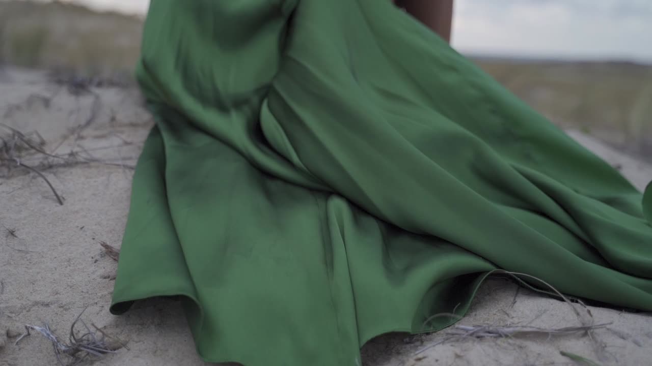 viento volando a través de un elegante vestido verde con clase en la playa de arena paisaje ventoso mujeres sentadas - cámara lenta cinemática