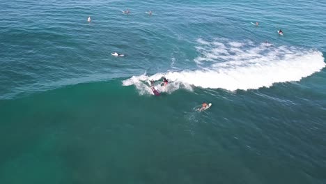 dos surfistas compartiendo una ola en la playa de waikiki en honolulu hawaii con agua azul cristalina y otros surfistas rodeándolos, muñeca aérea