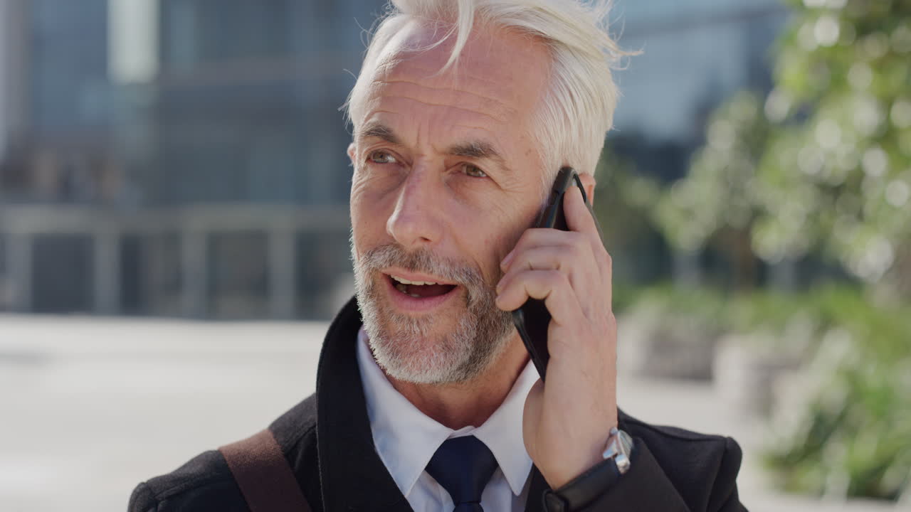portrait successful mature businessman using smartphone answering phone call enjoying talking conversation on mobile phone professional entrepreneur chatting in city slow motion