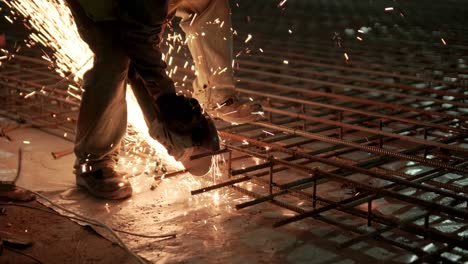 trabajador industrial está cortando barras de refuerzo metálicas con una sierra circular. construcción de una fábrica, hangar
