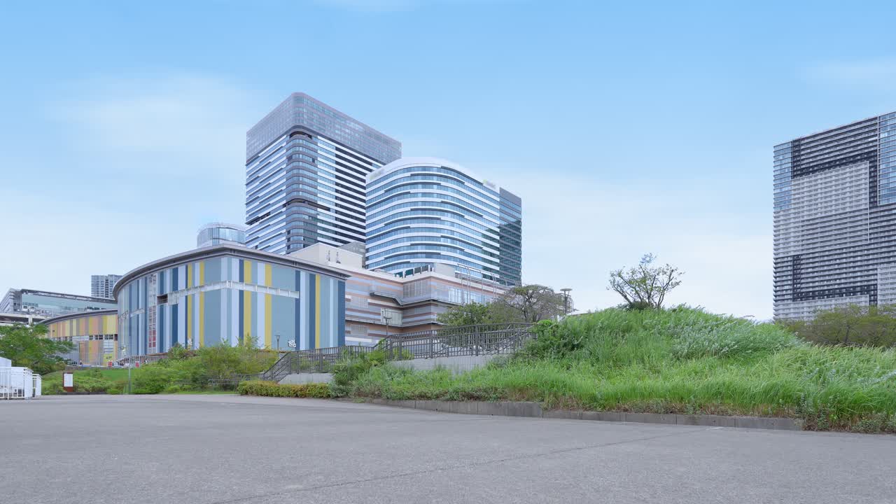 A low-angle shot of various modern, distinctively designed buildings in Tokyo's Toyosu area against a clear blue sky