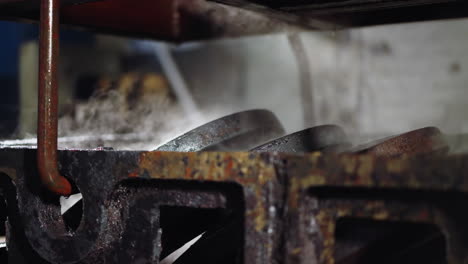 steam rises from freshly quenched metal parts in a casting foundry's cooling station