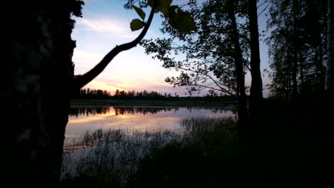 Silence-in-nature,-timelapse-of-summer-night-sky-reflected-in-calm-lake-in-Scandinavia