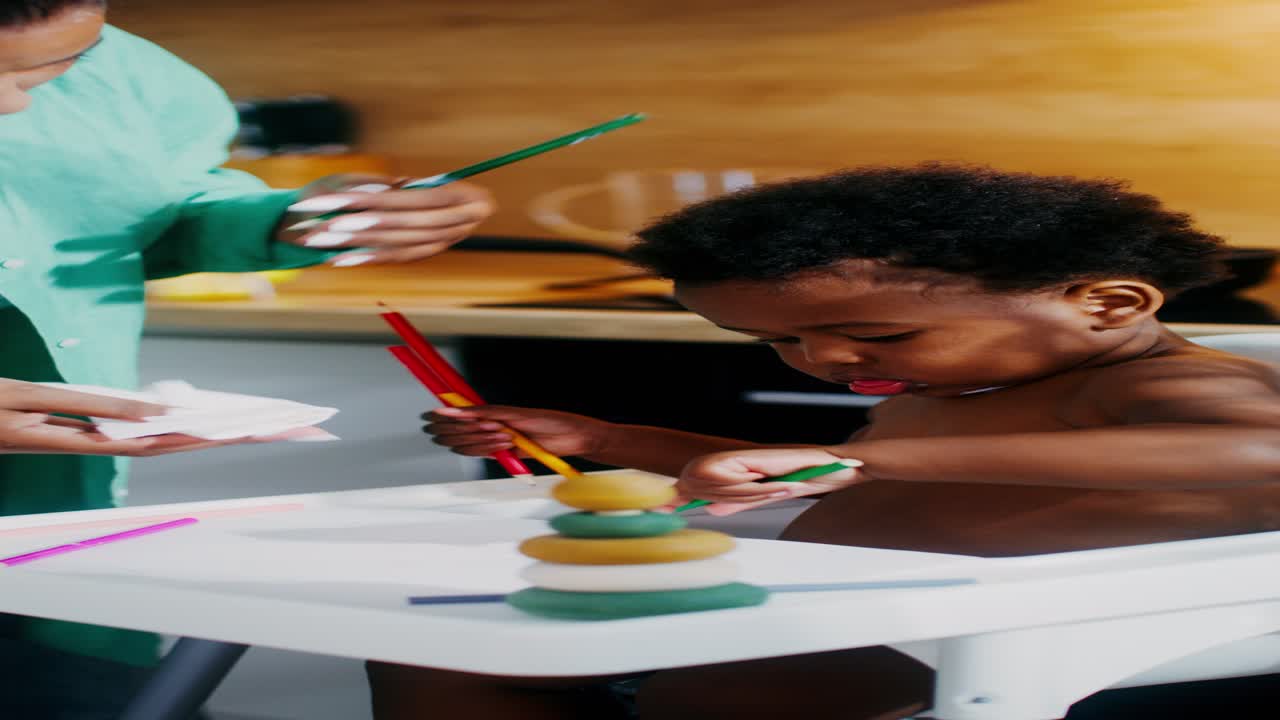 madre ayudando al bebé a limpiar los lápices de colores