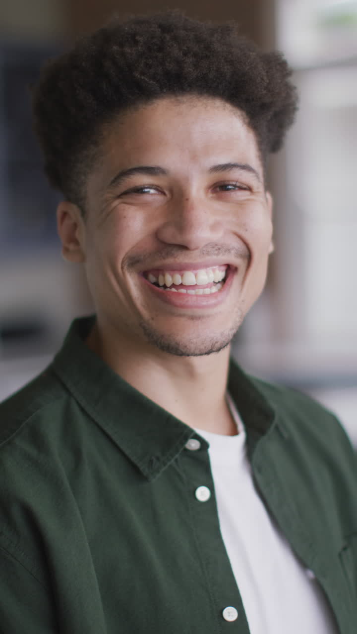retrato de video vertical de un hombre biracial sonriente relajándose en casa
