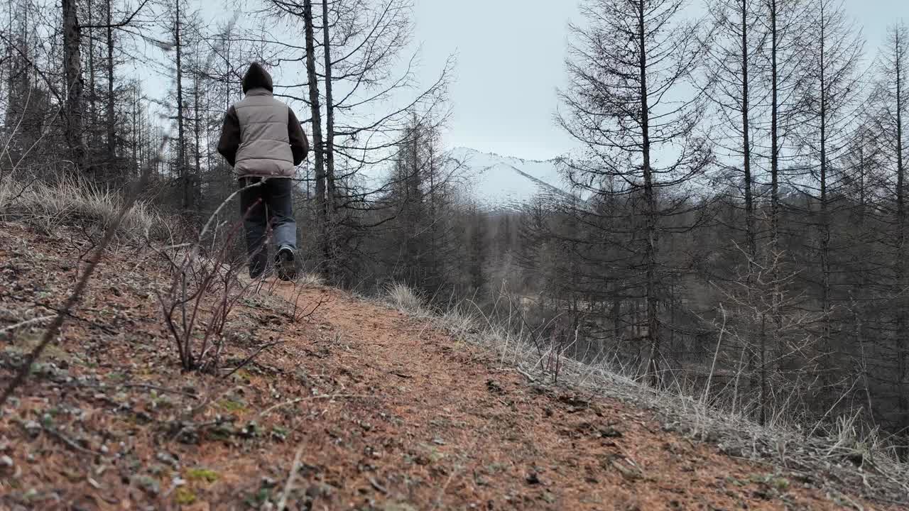 한 소녀가 봄의 회색 나무 숲에서 고 있습니다.