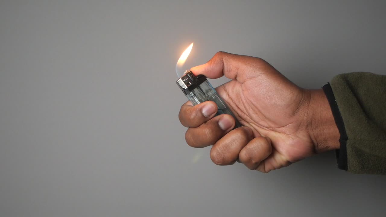 Hand holding a lighter with flame