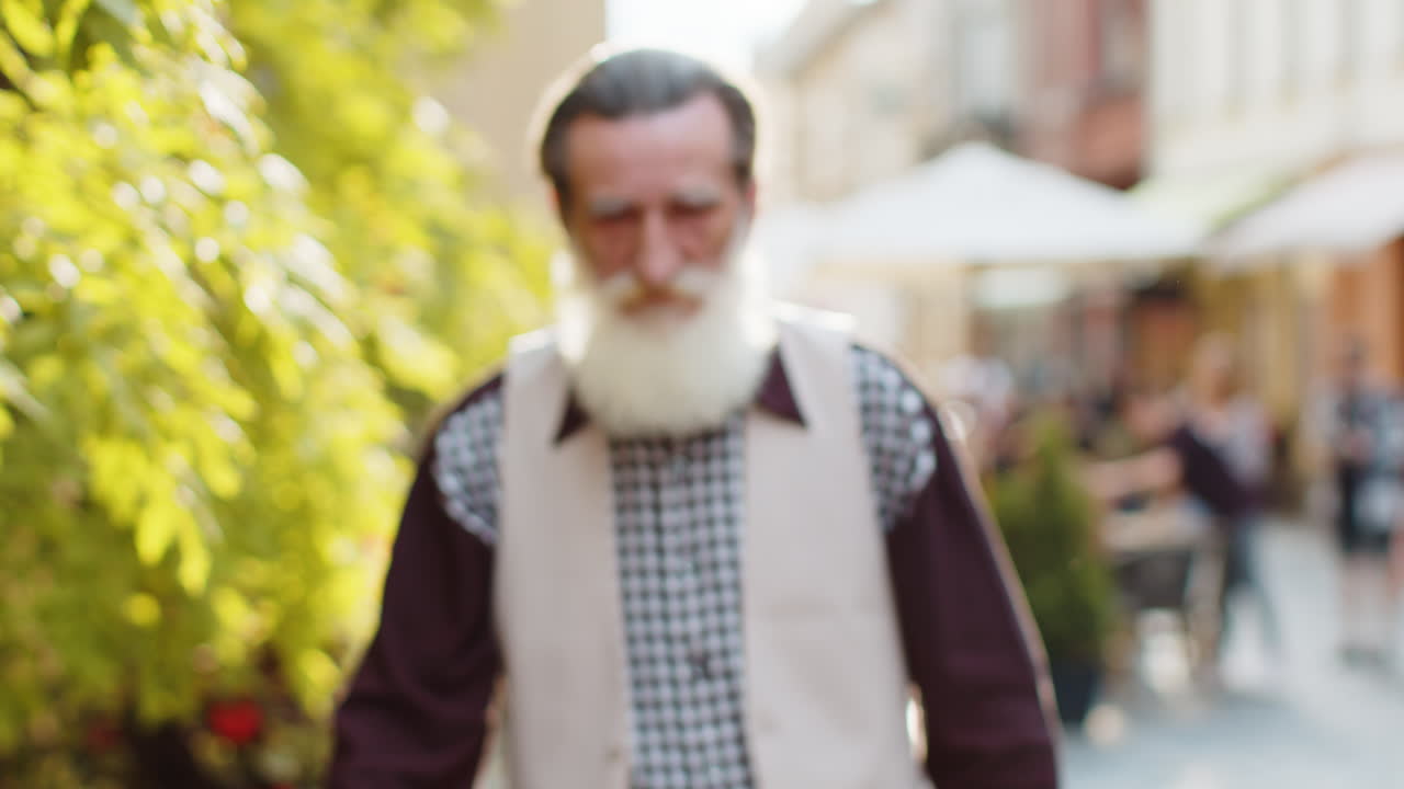 Angry displeased bearded senior old man upset sad dissatisfied looking at camera in city street
