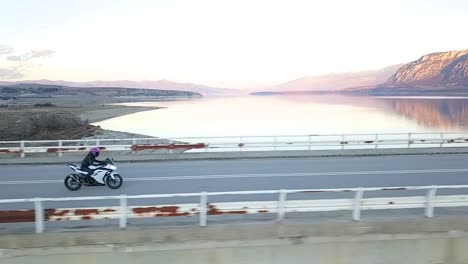 drone shot of a girl riding a super sport motorcycle and accelerating on a bridge over a lake in greece