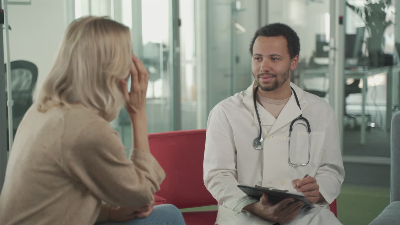 A Young Black Doctor Asking Questions To A Blonde Woman