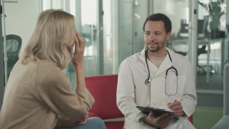 a young black doctor asking questions to a blonde woman