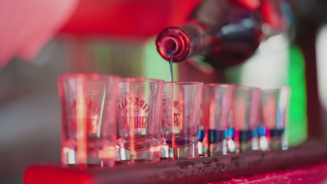 el camarero llena pequeños vasos con bebidas en la encimera de primer plano. los camareros hacen tiradores para la fiesta en el club nocturno. el camarero hace bebidas duras para los invitados