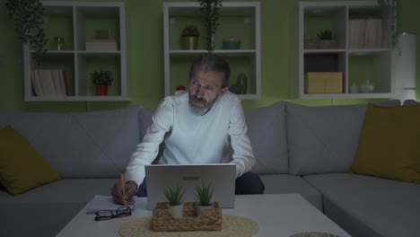 a middle-aged man working on a laptop experiences a power outage in his home.