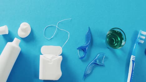 Video-of-close-up-of-floss-and-toothbrush-on-blue-background