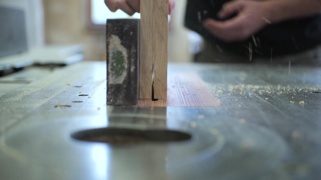 carpenter cutting wooden frame in half with circular saw, frontal view, slow motion