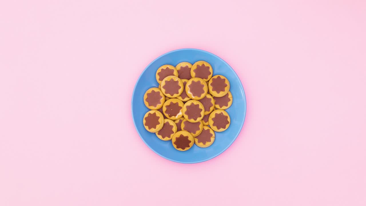 Cookies in blue plate move in circle on pink theme. Stop motion