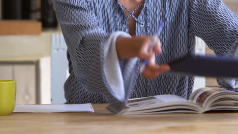 woman researching and making notes at kitchen table, close up, shot on r3d