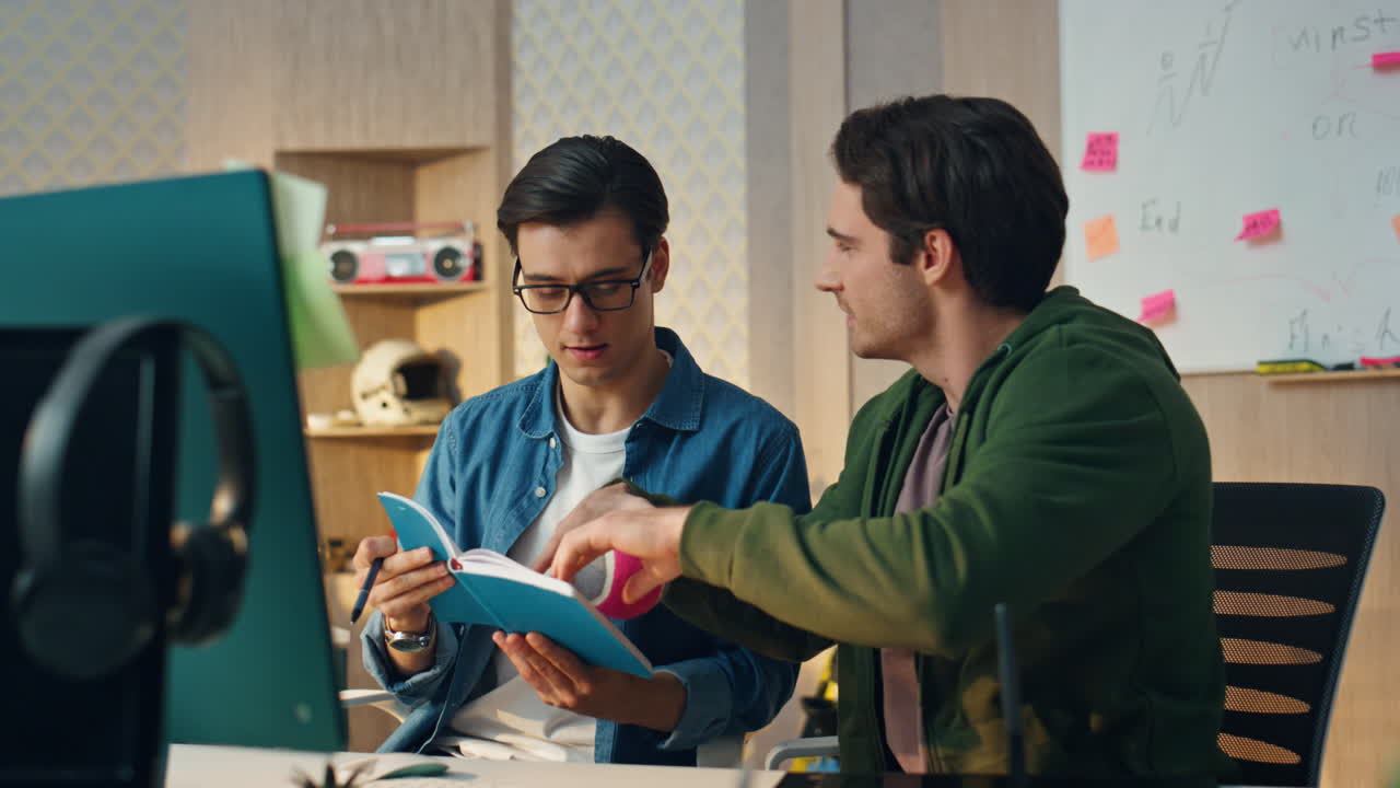 los chicos de la startup discutiendo el cuaderno volviendo páginas en la oficina. llamada de video del equipo