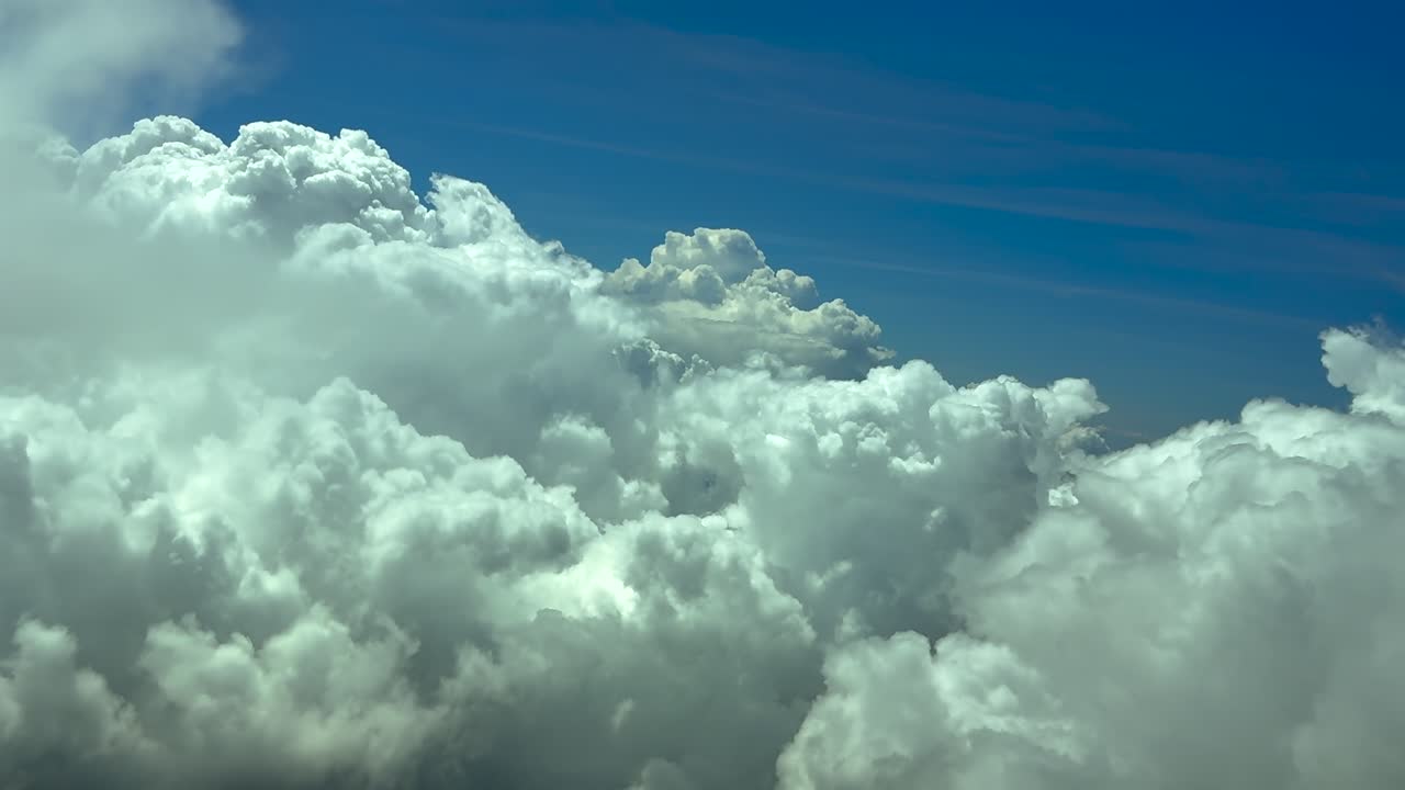 Pilotperspektiv flyvende i en turbulent himmel med truende stormskyer forude under en blå himmel. Scene optaget i 12000 meters højde fra et jetfly.