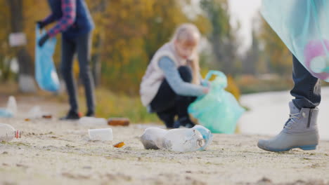 a group of volunteers picks up trash on the lake stacks plastic waste in bags