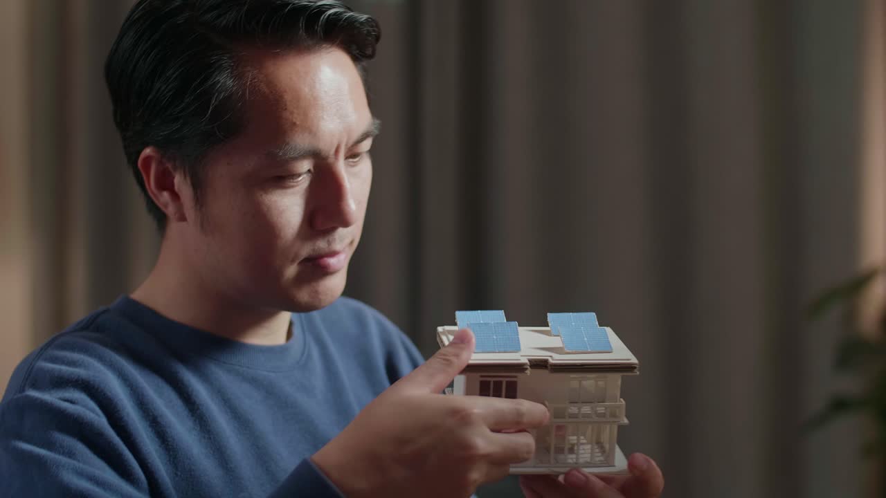 태양 전지 패널 을 가진 모형 집 을 조사 하는 사람