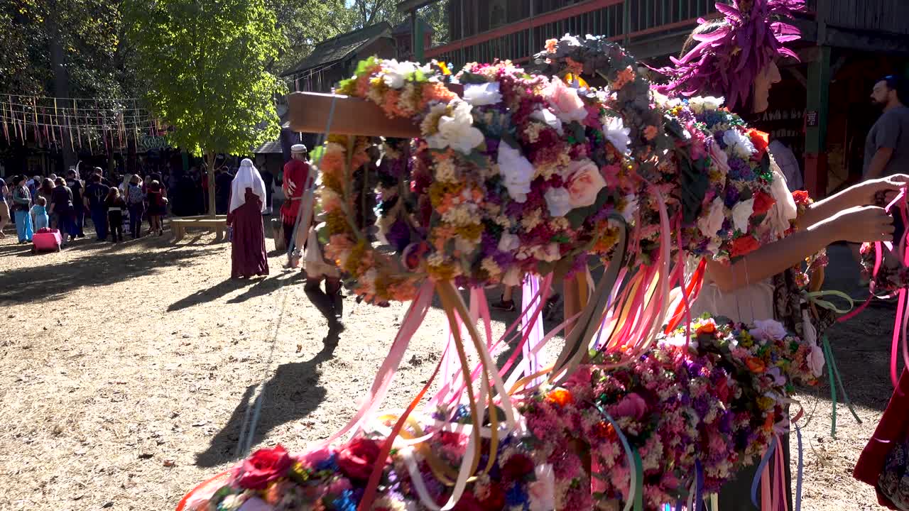 Pretty teenage girl selling flowered and feathered head pieces at a Renaissance Festival.