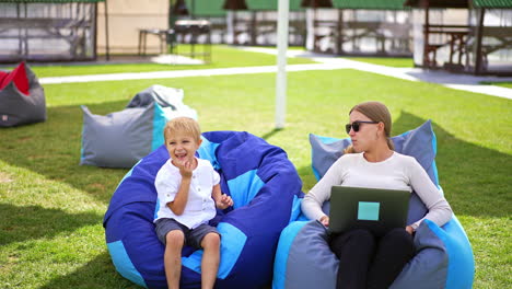 mother and son relaxing outdoors with laptop