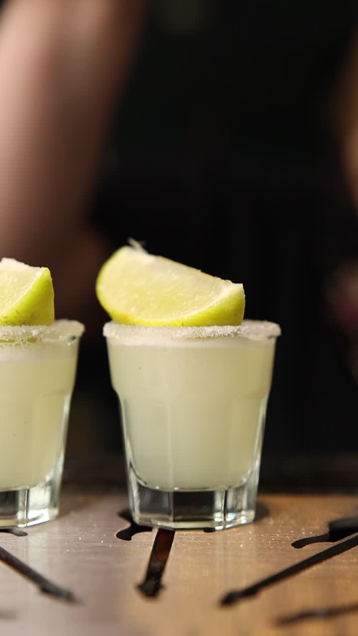 Barman che guarnisce bicchierini da shot con spicchi di lime fresco