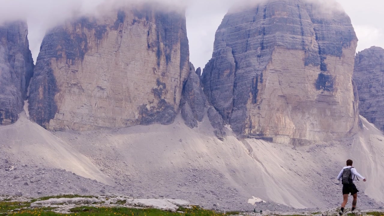 Yalnız bir gezginin daha yakından görmek için Dolomitler'e doğru koştuğu, sağa doğru kayan yakın çekim drone görüntüsü.