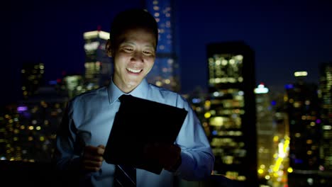 asian businessman using tablet on rooftop at night