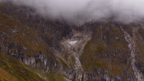 Ice-glacier-on-mountain-peaks-in-Autumn-fall-orange-grass-colors,-aerial-view