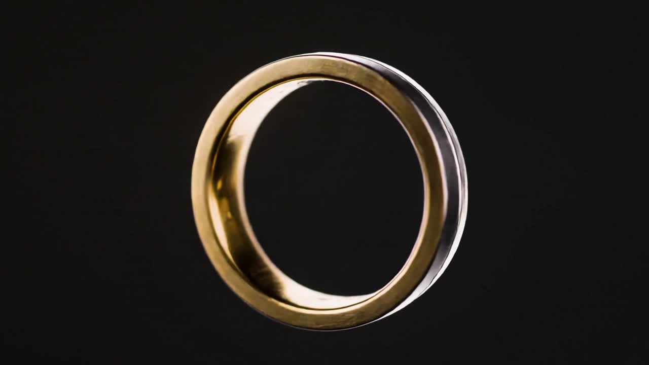 Anello metallico bicolore rotante che gira su un asse verticale all'inizio del video in studio, rivelando la finitura