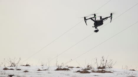 gran dron profesional dji inspire 2 con cámara de video vuela bajo sobre la nieve mientras sopla un fuerte viento-1