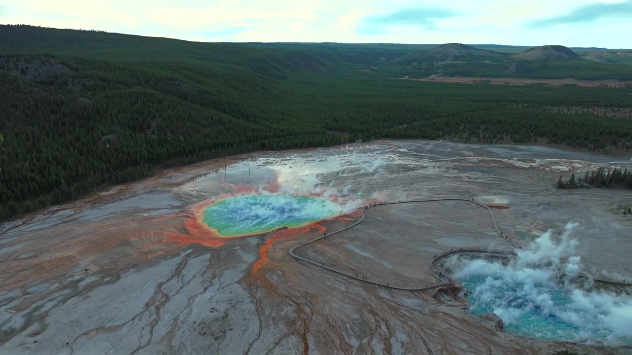 Udsigtspunkt ved Grand Prismatic Springs, Mid Geyser Basin gangbro, Yellowstone Nationalpark, Wyoming. Luftfoto med drone af naturlandskab, overskyet morgen, blå himmel, farverige varme kilder og bassiner i tilbagetrækkende bevægelse