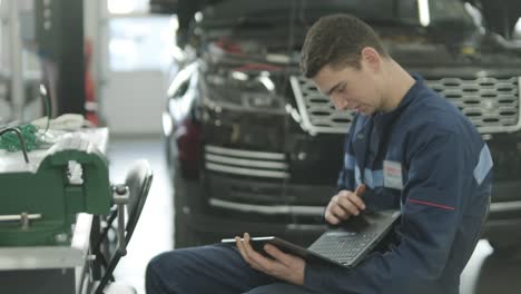 mechanic performing car diagnostics with laptop