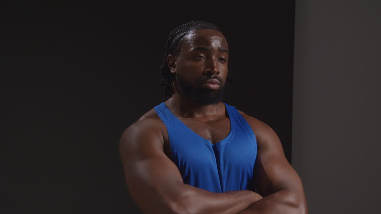 retrato de estudio de un atleta masculino con chaleco sudando después de un entrenamiento deportivo o ejercicio en el gimnasio doblando los brazos 2