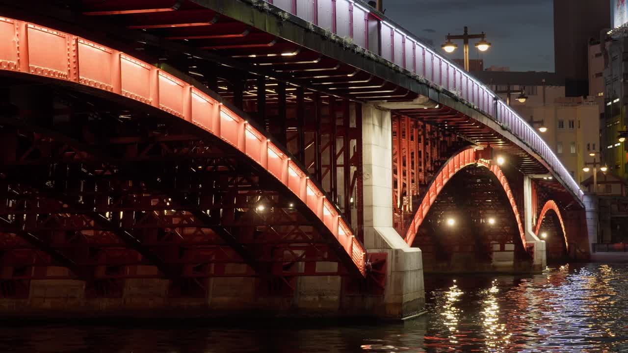 Night view of a red bridge over a river in a city