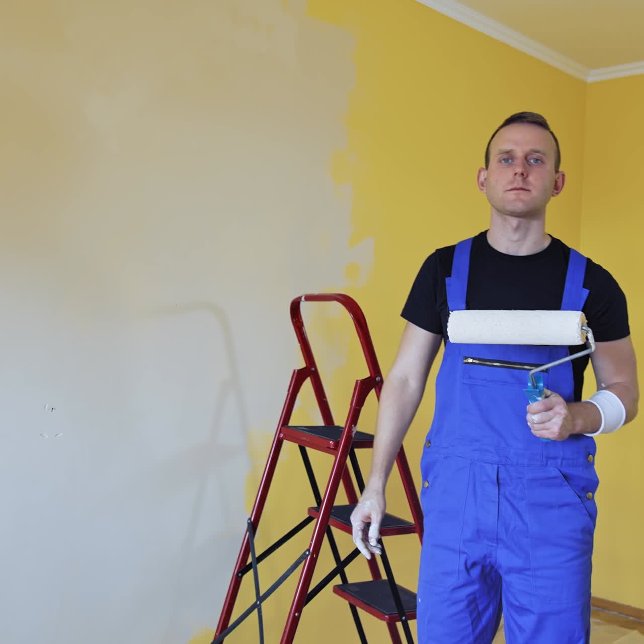 Man painting with roller. Workman in the uniforms painting the walls with paint roller
