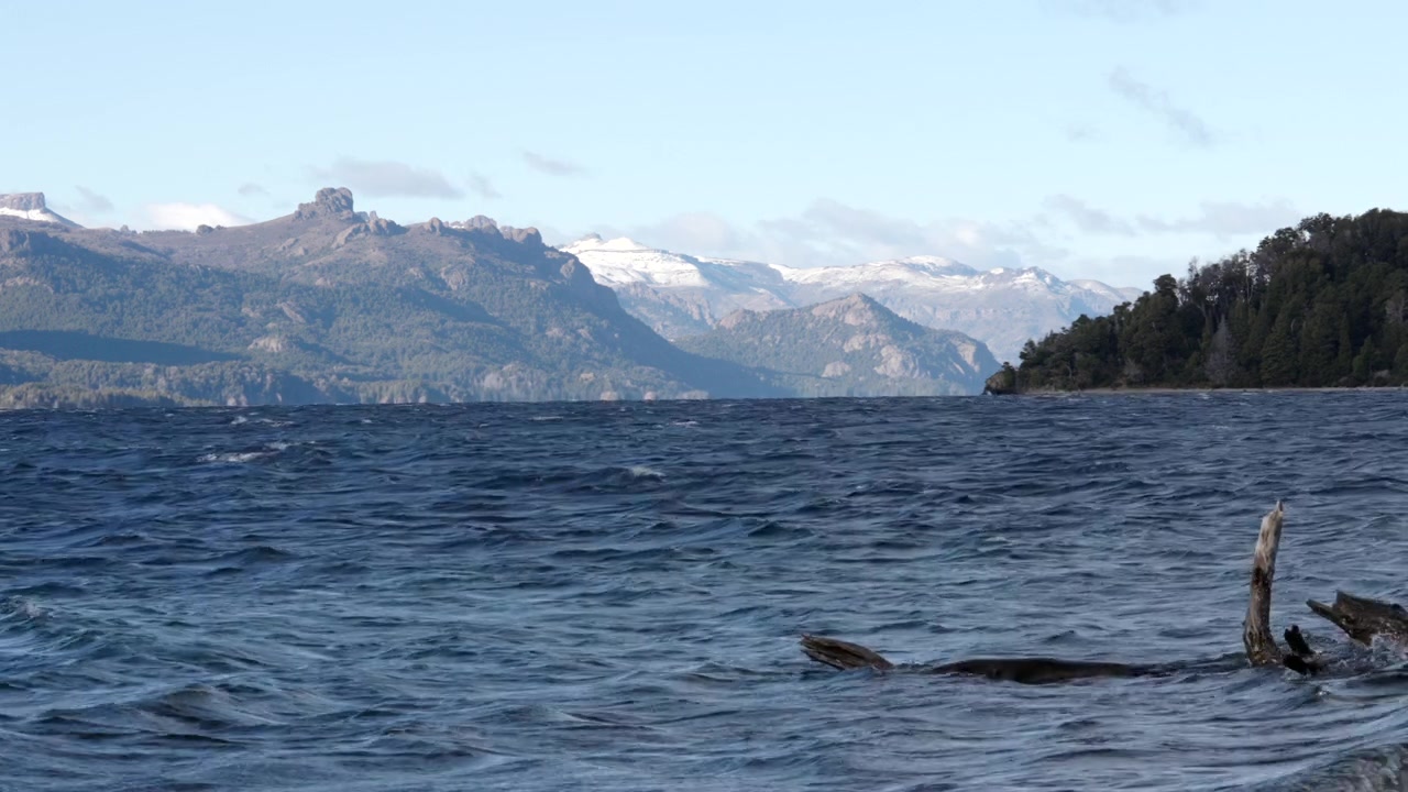 Lago ventoso in Patagonia con onde forti e montagne, ideale per scene naturalistiche drammatiche e narrazione ambientale.