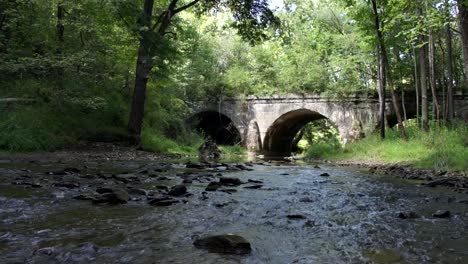 slow tilt up shot of river and oid stone bridge