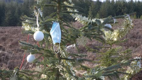 decorated christmas tree with face mask blowing in the wind at wicklow mountains in dublin, ireland