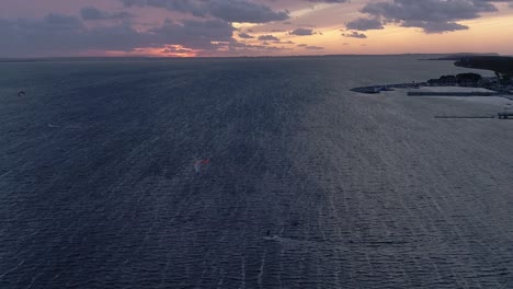 Silueta-De-Un-Hombre-En-Una-Tabla-De-Cometas-En-El-Mar-Al-Atardecer,-Vista-Aérea